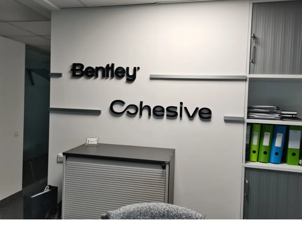 Litery Bentley i Cohesive na ścianie w biurze