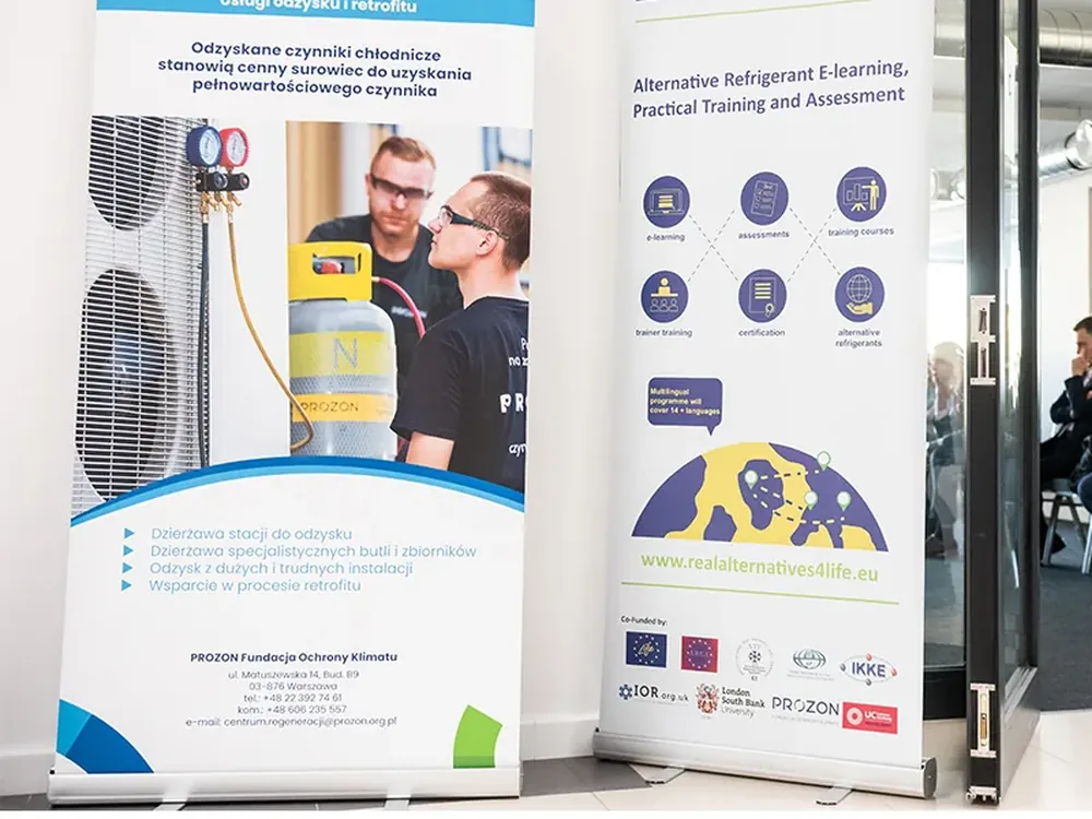 Dwa rollupy reklamowe z grafiką firmową przy wejściu na salę