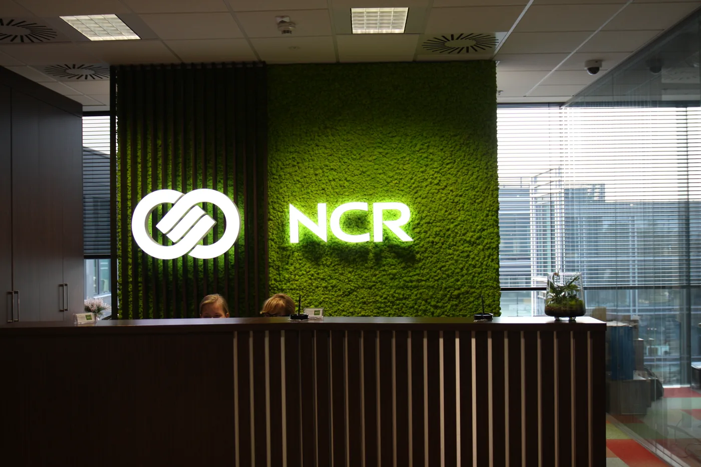 Recepcja NCR: podświetlane logo na ścianie z mchu
