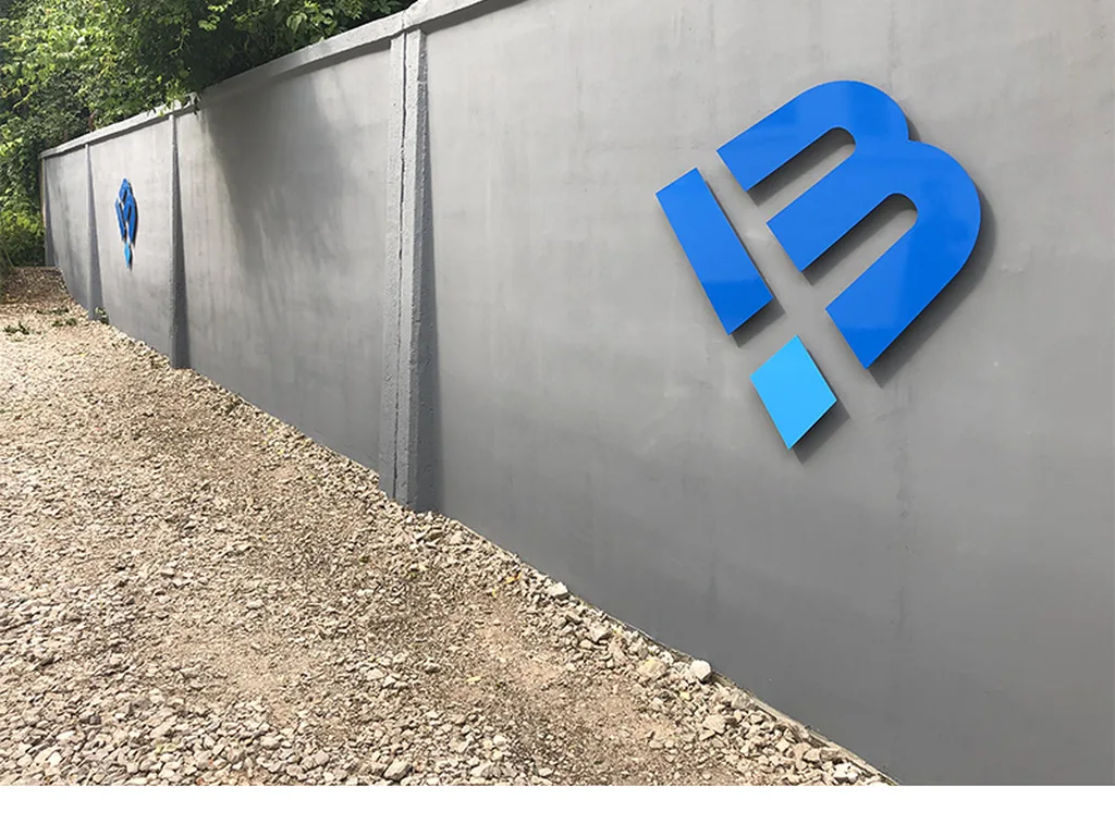 Przestrzenne logo z pleksy zamontowane na elewacji